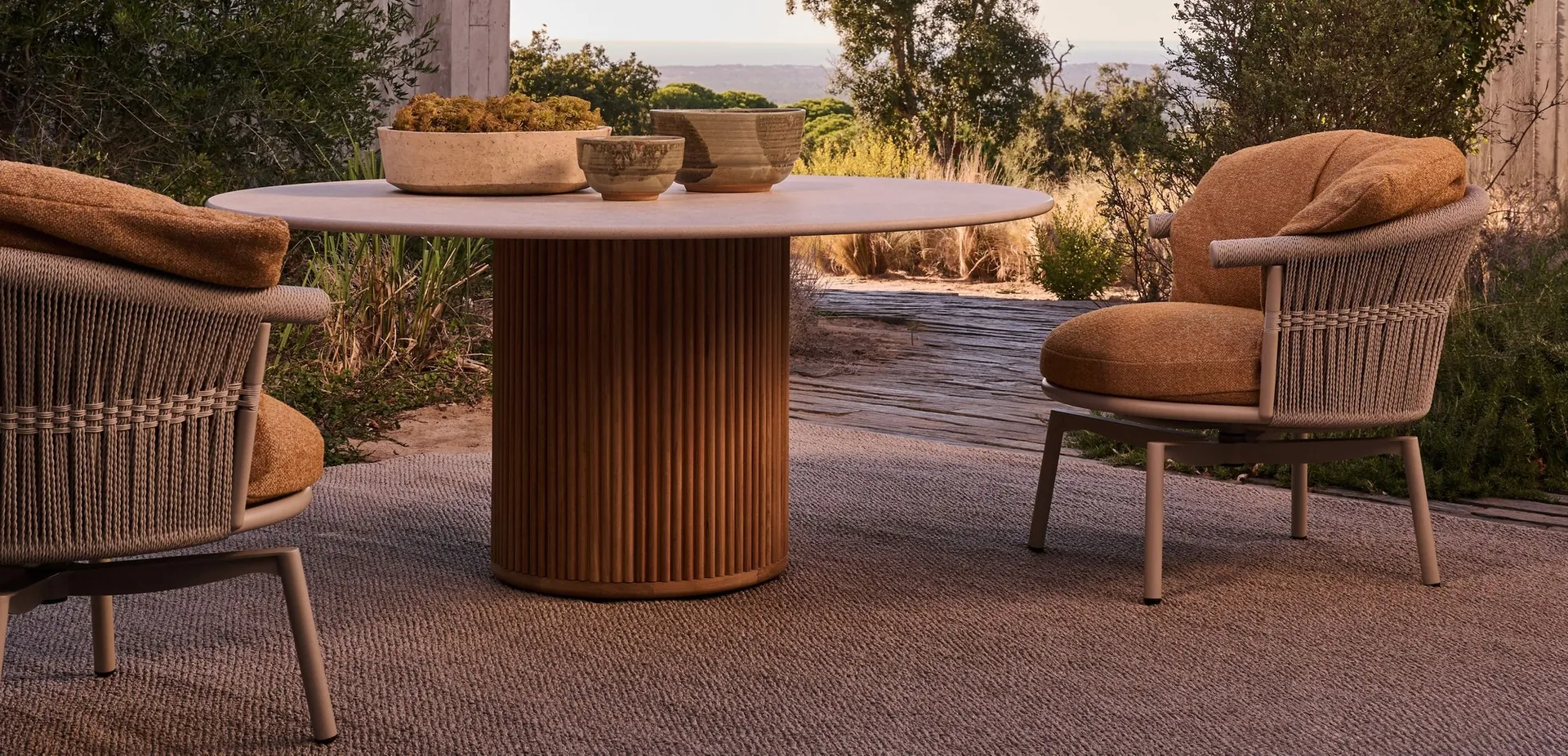Tribù Cesta swivel lounge chair with a rope-woven back and deep cushions on a poolside terrace