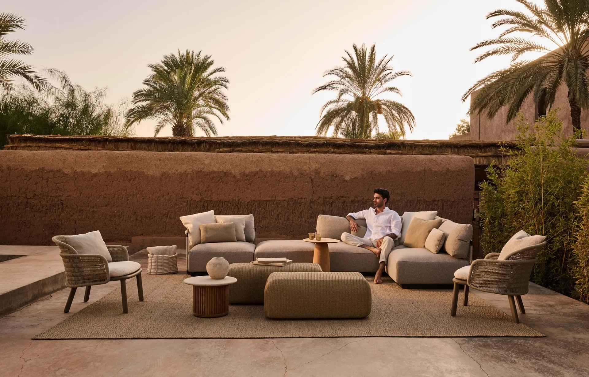 Tribù Suro armchairs with rope-wound backs and wooden legs on a walled terrace at dusk
